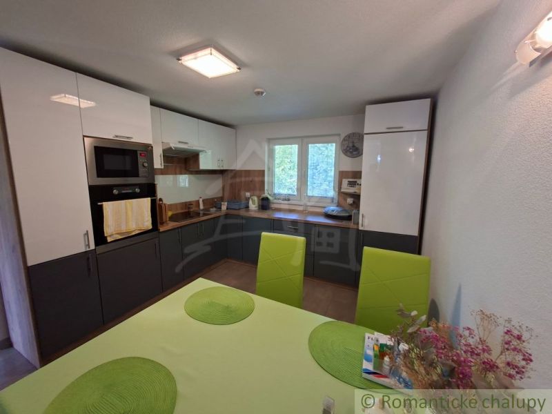 A kitchen in a family house with green chairs and built-in appliances.