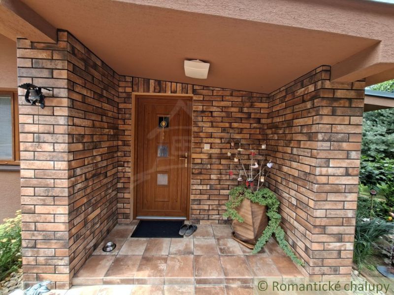 The entrance to the family house in Veľké Uherce with a brick wall and paving.