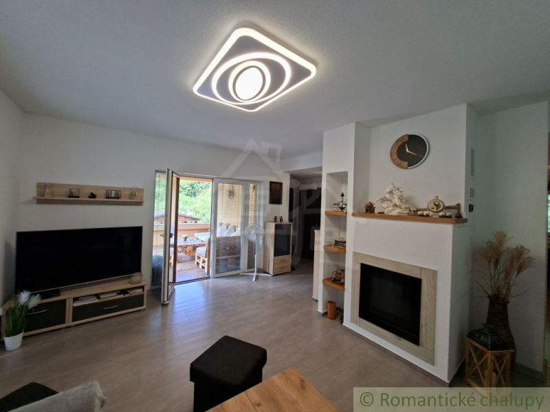 Living room in a family house with a fireplace, television, and wooden decor flooring.