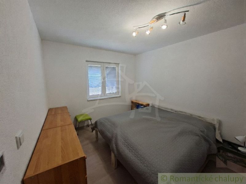 Bedroom in a family house with a bed, cabinet, and ceiling lamps.