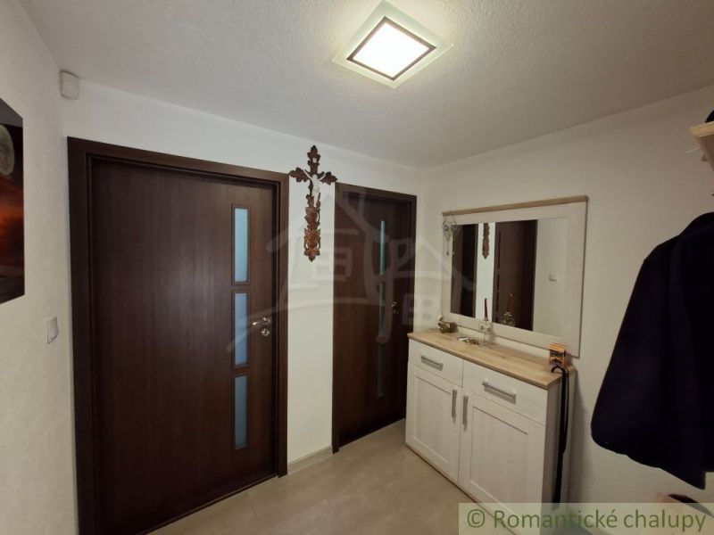 The family house has an entrance hall with white furniture, a mirror, and wooden doors.