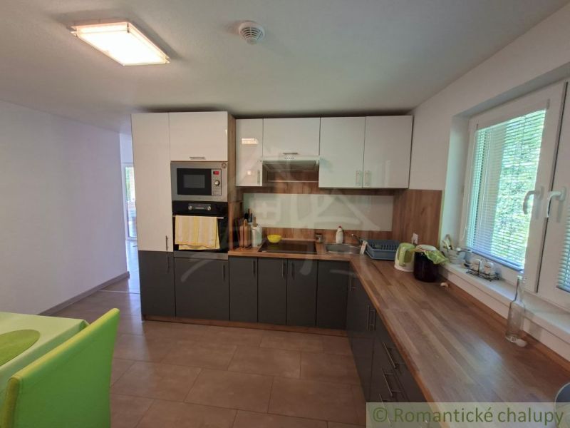 A kitchen in a family house with corner cabinets, white appliances, and a view from the window.
