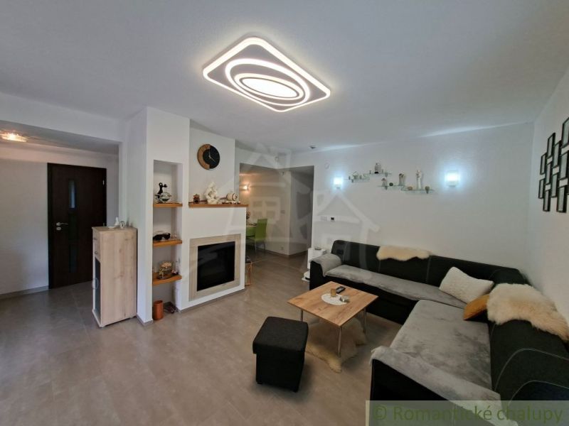 Living room with a fireplace, large sofa, and wood-patterned flooring in a family house.
