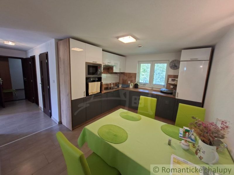 A kitchen in a family house with white cabinets and a table with colorful chairs.