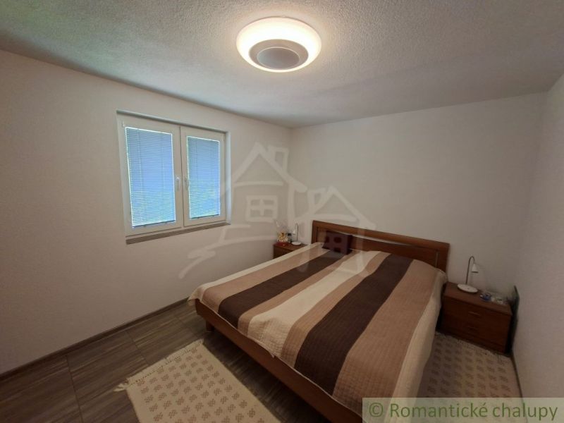 Bedroom with a double bed, nightstands, and a wooden decor floor in a family house.