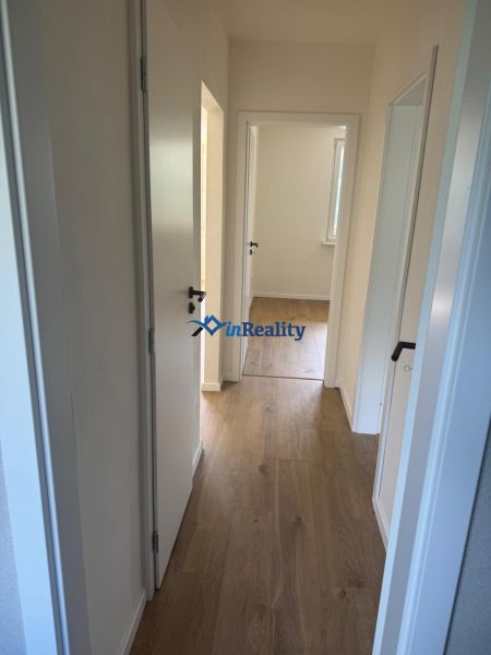 A hallway with white doors and a wooden decor floor in a 3-room apartment.