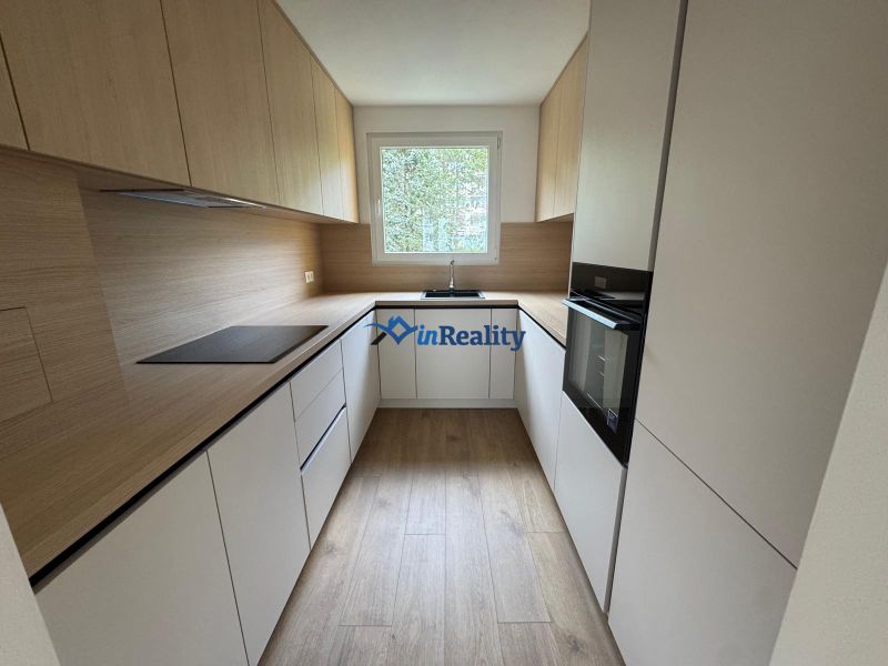A kitchen with white cabinets and a wood-patterned floor in a 3-room apartment.