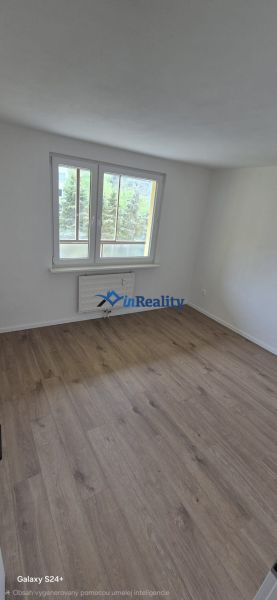 A room in a 3-room apartment with a window and a floor with a wooden decor.