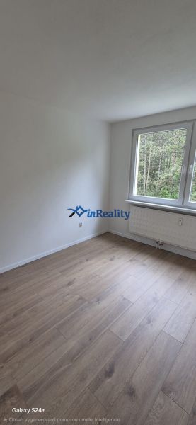 A room in a 3-room apartment with white walls and a wooden decor floor.