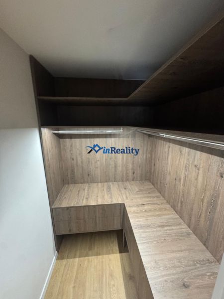 A wardrobe in a 3-room apartment with shelves and a wooden decor floor.