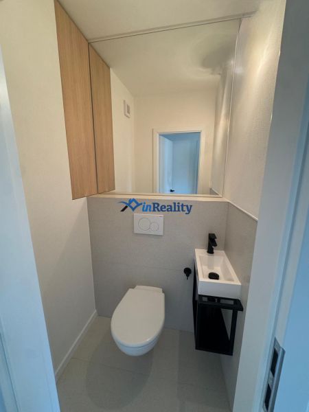 A bathroom in a 3-room apartment with a toilet, sink, and storage cabinets.