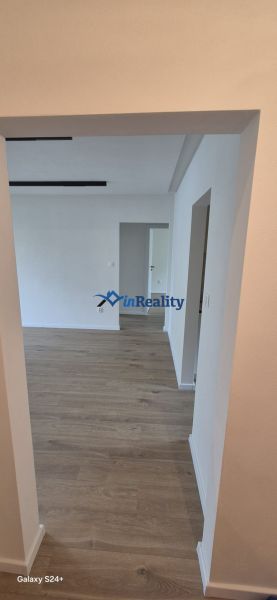 A hallway with entrances to rooms and a floor with a wooden decor in a 3-room apartment.