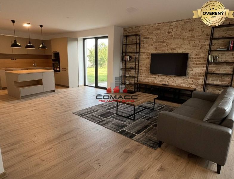 A bright living room in a family house with a wood-patterned floor and a brick wall.