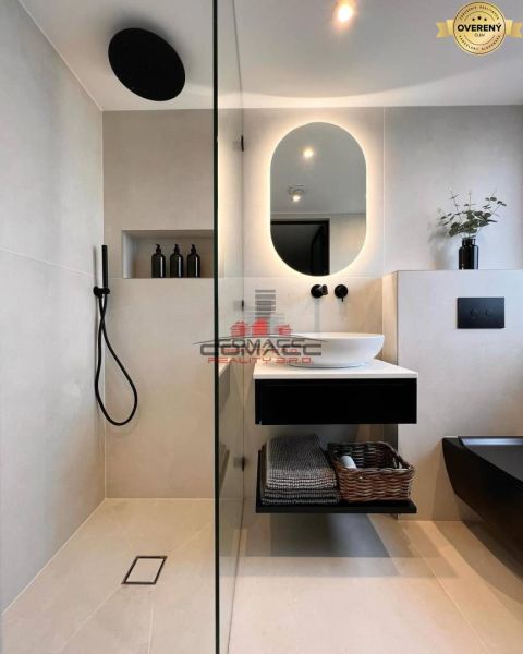 A bathroom in a family house with a sink, shower, basket, and mirror.