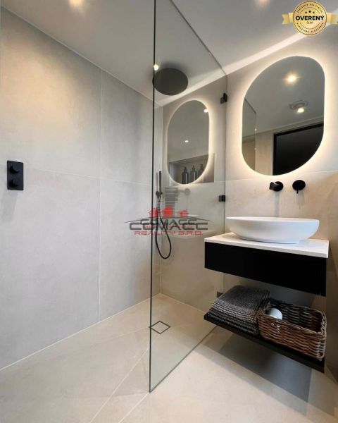 A bathroom in a family house with a large mirror and a shower enclosure.
