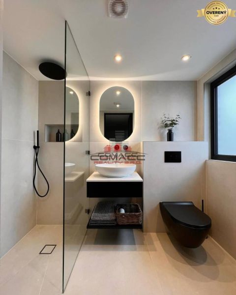 A bathroom in a family house with a black sink, ceiling lights, and a shower corner.