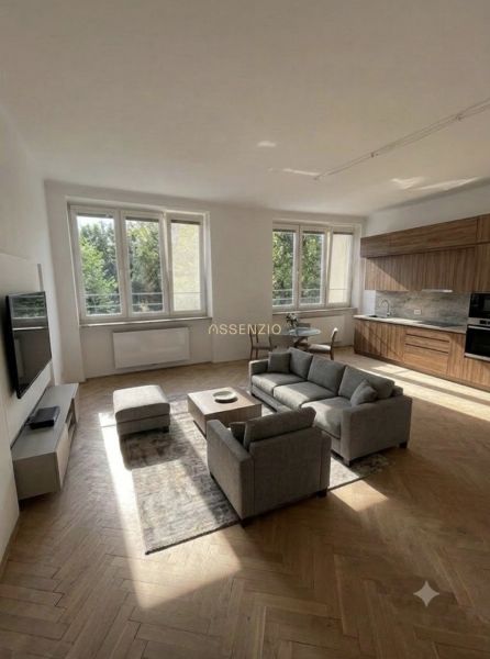 A bright living room space with a sofa, dining table, and wood-decor flooring in a three-room apartment.