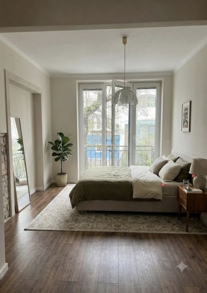 A bedroom in a 3-room apartment with large windows and a wooden decor floor.