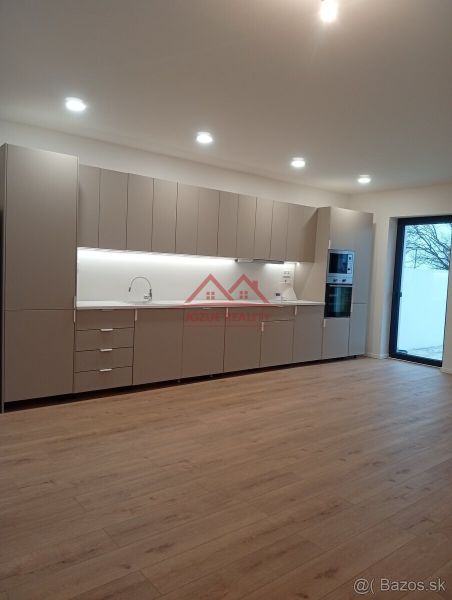 A kitchen in a family house with a wooden decor floor and built-in appliances.