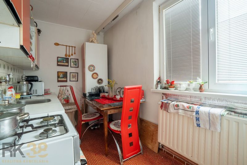 A kitchen in a family house with a table and red chairs, decorations on the wall.