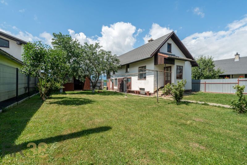 A family house on Športová Street in Hozelce with a lawn, trees, and a fence.