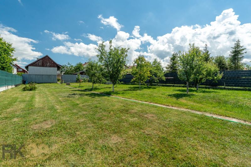 A garden at a family house on Športová Street in Hozelce, with a lawn and fruit trees.