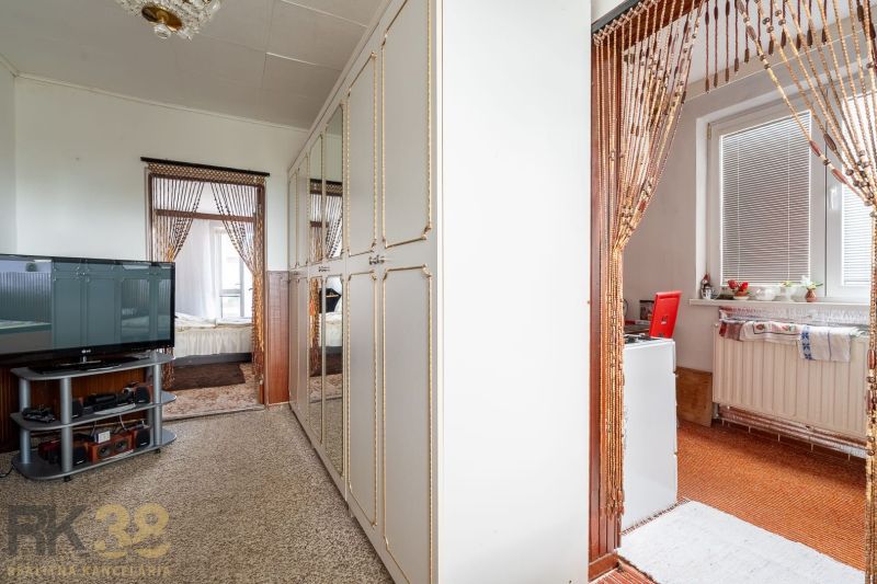 Interior of a family house with a television, mirrored wardrobe, and wooden bead curtains.