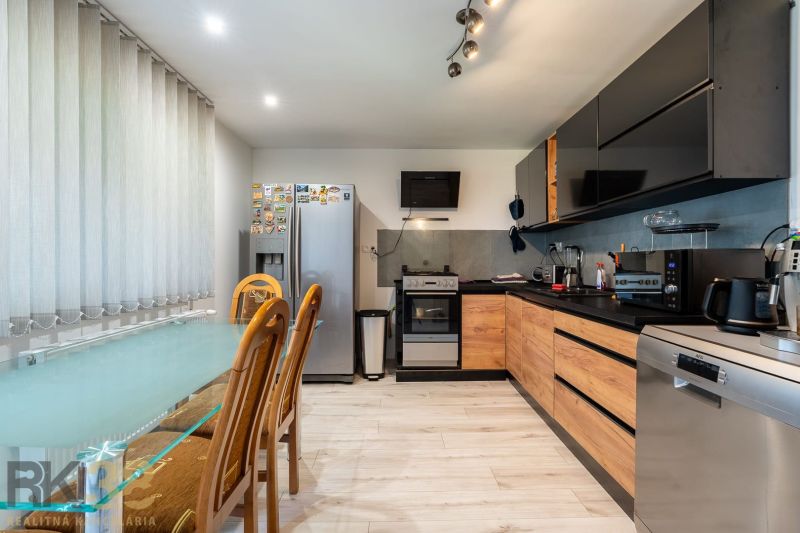 A kitchen in a family house with a wooden decor floor and a dining table.