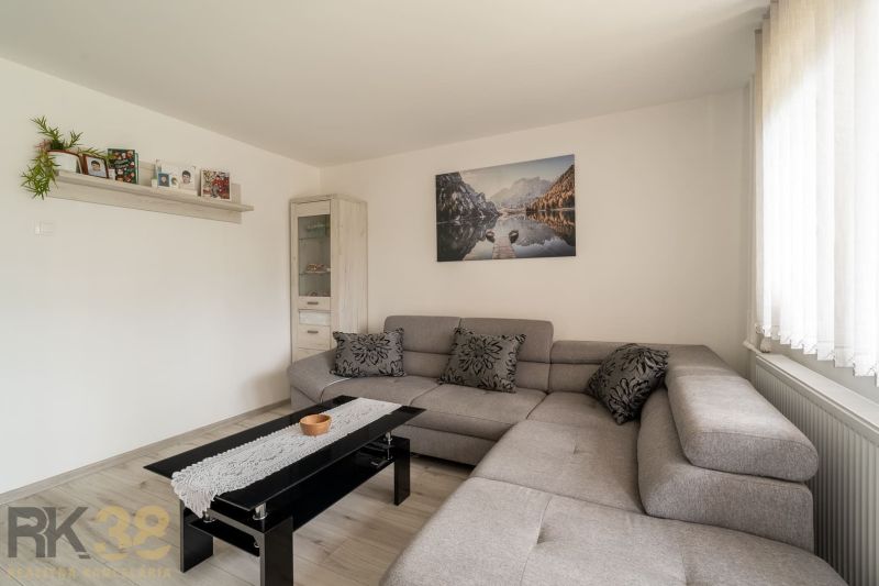 Living room in a family house with a gray sofa, pictures, and a floor with a wooden decor.