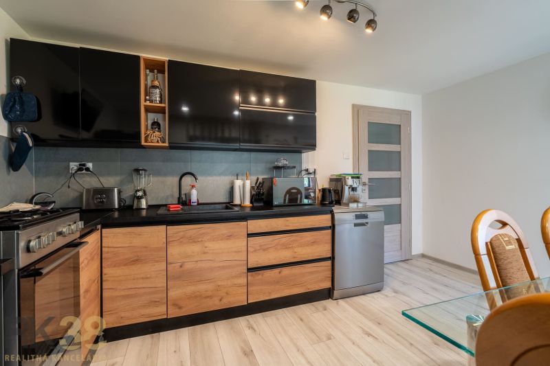A kitchen in a family house with black cabinets, wooden decor, and appliances.