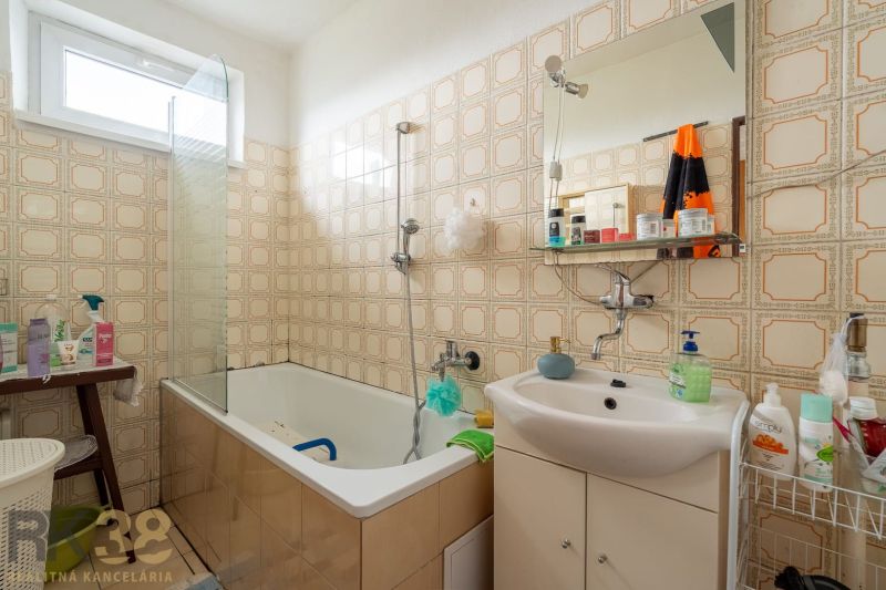 A bathroom in a family house with a bathtub, a sink, and retro tiles.