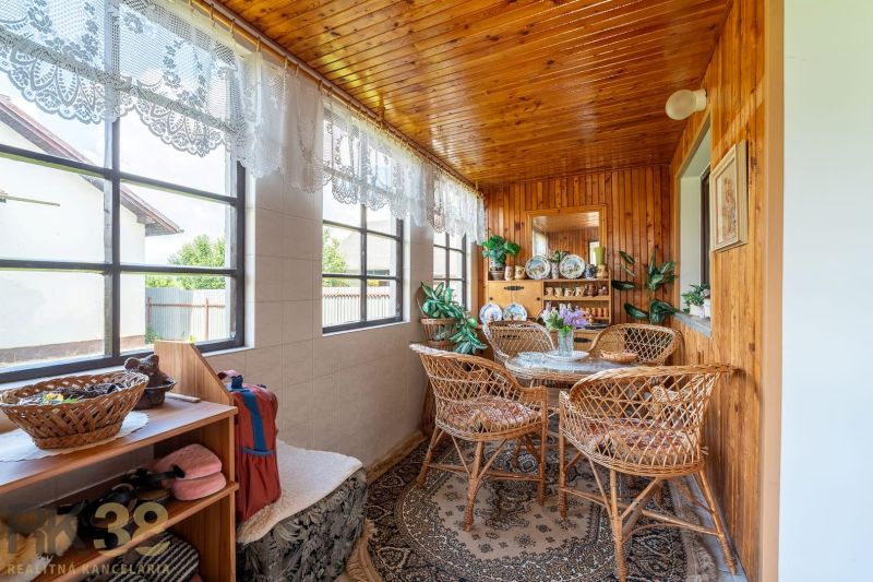 A pleasant terrace in a family house with rattan furniture and a wooden ceiling.