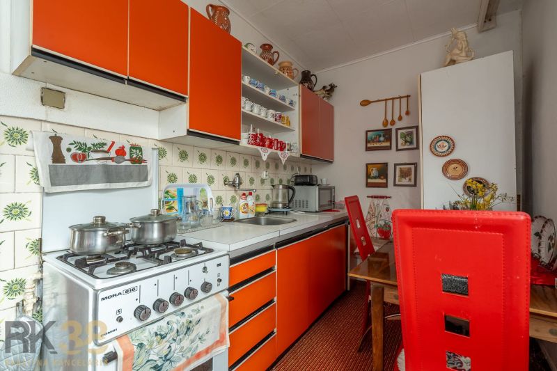 A kitchen in a family house with an orange cabinet, a stove, and decorative items on the walls.