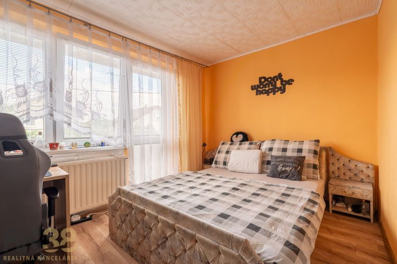 A bedroom in a family house with a bed, a desk, and a floor with a wooden decor.