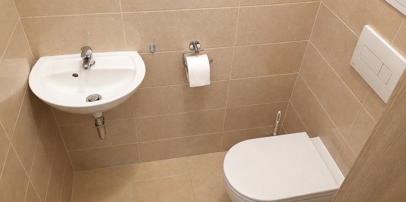 Bathroom with toilet, sink, and beige tiles in a studio apartment.