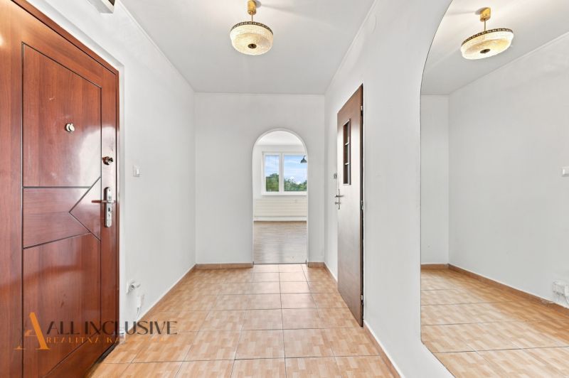 A hallway in a 2-room apartment with a wooden decor floor and a mirror on the wall.