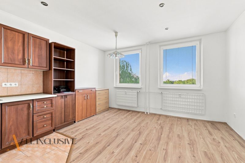 A kitchen in a 2-room apartment with a wooden decor floor, cabinets, and windows.