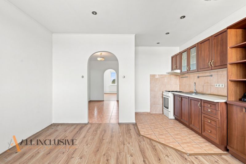 A kitchen in a 2-room apartment with a wooden decor floor and built-in cabinets.