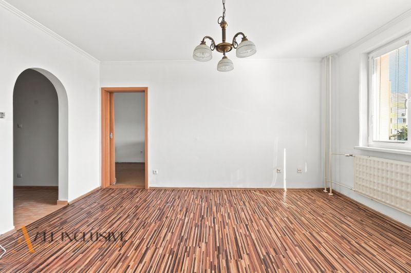 A room in a 2-room apartment with a wooden decor floor and a chandelier.