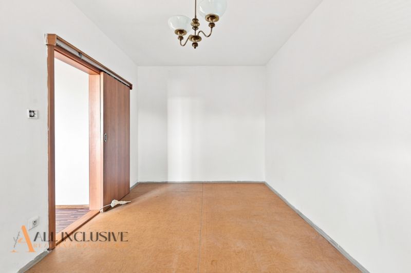 A room in a 2-room apartment with a wooden decor floor and sliding doors.