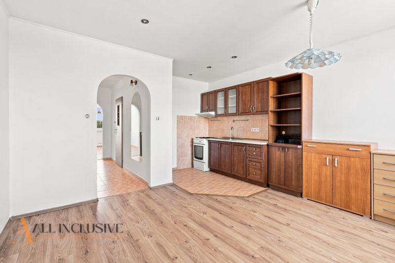 A kitchen in a 2-room apartment with a wooden decor floor and built-in cabinets.