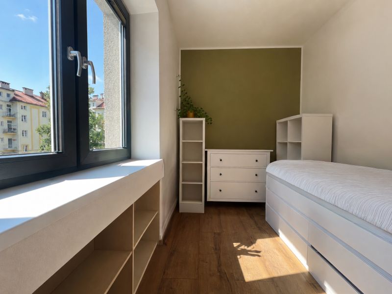 A cozy room with a wood-patterned floor in a 2-room apartment, overlooking the street.