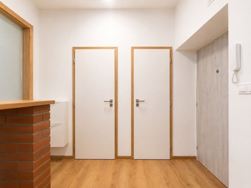 Entrance hallway in a 2-room apartment with white doors and a floor with a wood decor.