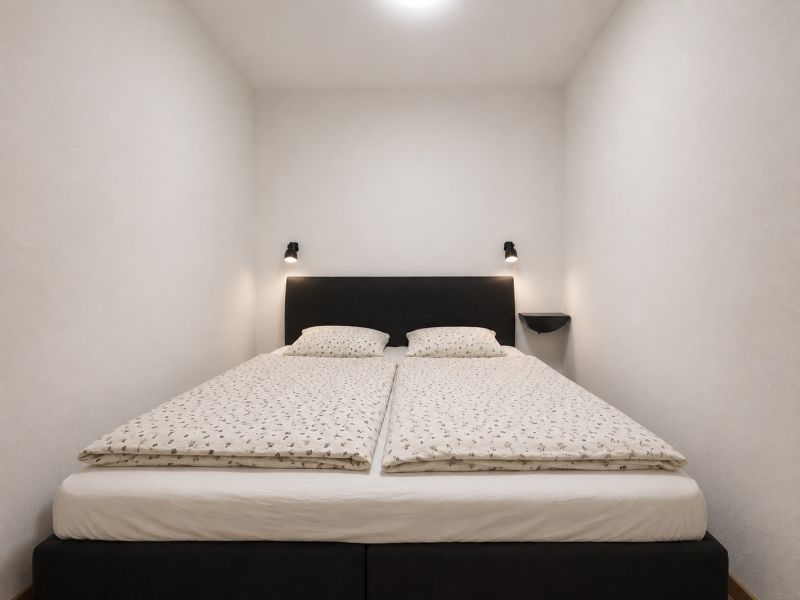 Bedroom in a 2-room apartment with a simple double bed and white bedding.