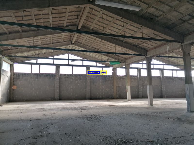 Warehouse and hall space with concrete flooring and a roof with steel beams.