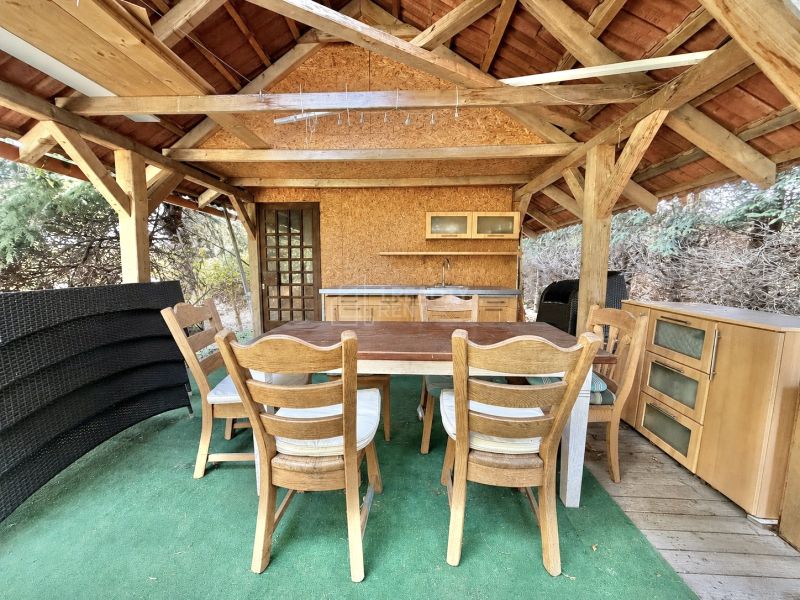 The gazebo of a family house in Mojš with wooden furniture and a green carpet.