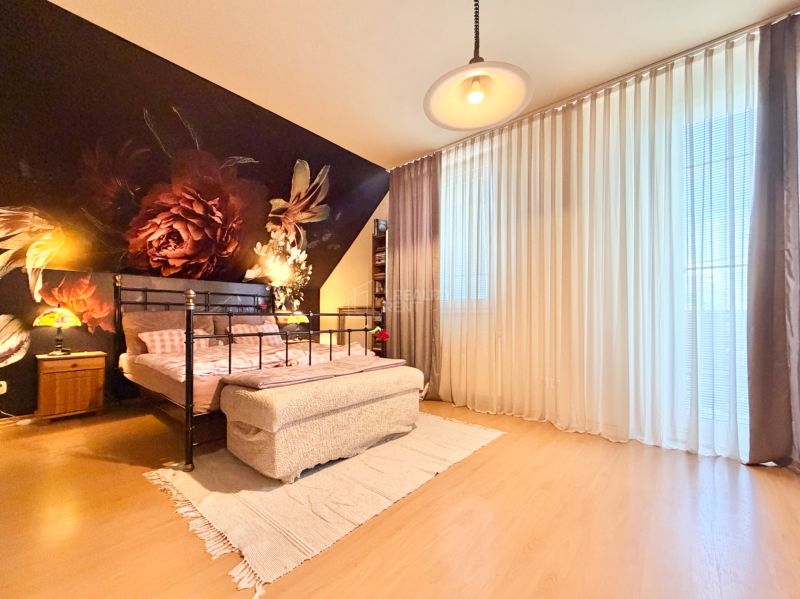 A bedroom with a dark floral motif, a metal bed, and a floor with a wooden decor.