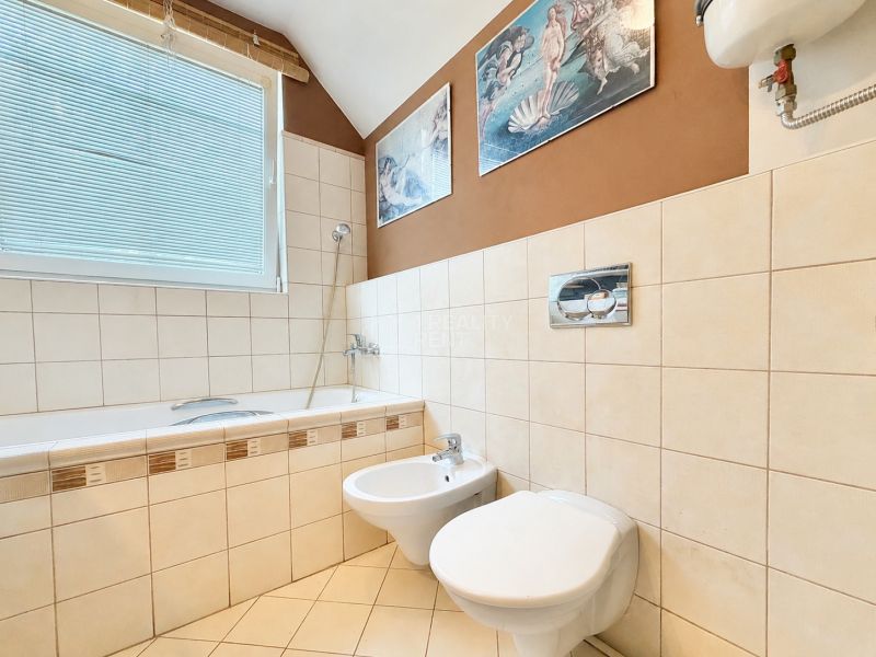 The bathroom in the family house contains a bathtub, a bidet, a toilet, and decorative tiles.