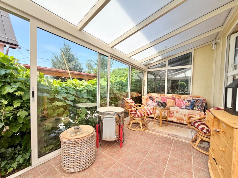 A winter garden in a family house with comfortable seating and a view of the garden.