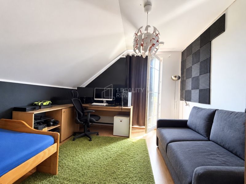 A room with a desk, sofa, bed, and acoustic panels in a family house.